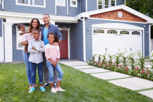 family of 3 standing in front of their home